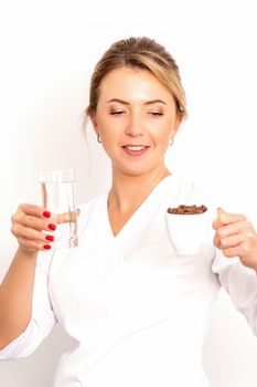 Coffee with water. The female nutritionist holds a cup of coffee beans and a glass of water in her hands on white background