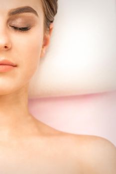 Close up of half-face of a serene young woman is lying with closed eyes top view, copy space