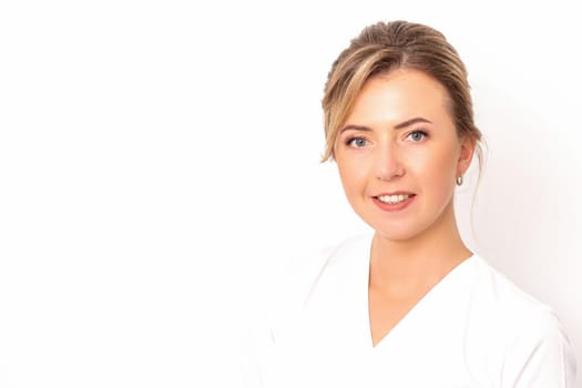 Close-up portrait of young smiling female caucasian healthcare worker standing staring at the camera on white background