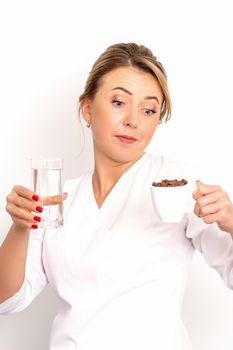 Coffee with water. The female nutritionist holds a cup of coffee beans and a glass of water in her hands on white background