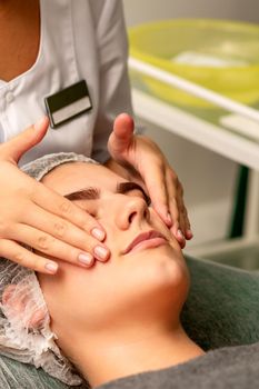 Face massage. Beautiful caucasian young white woman having a facial massage with closed eyes in a spa salon