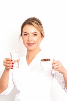 Coffee with water. The female nutritionist holds a cup of coffee beans and a glass of water in her hands on white background