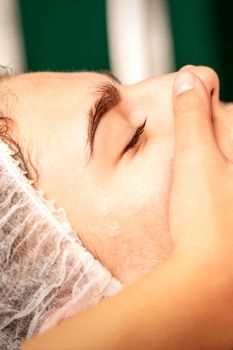 Face massage. Beautiful caucasian young white woman having a facial massage with closed eyes in a spa salon