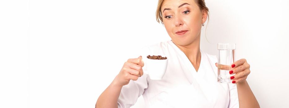 Coffee with water. The female nutritionist holds a cup of coffee beans and a glass of water in her hands on white background