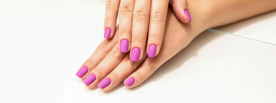 Beautiful manicure with purple, pink nail polish on young caucasian female hands