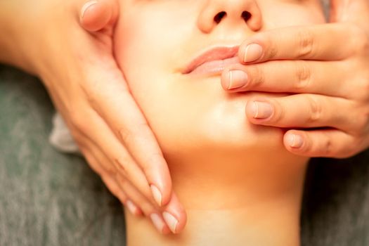 Beautiful young caucasian woman with closed eyes receiving a facial massage in a beauty salon