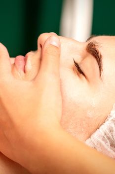 Face massage. Beautiful caucasian young white woman having a facial massage with closed eyes in a spa salon