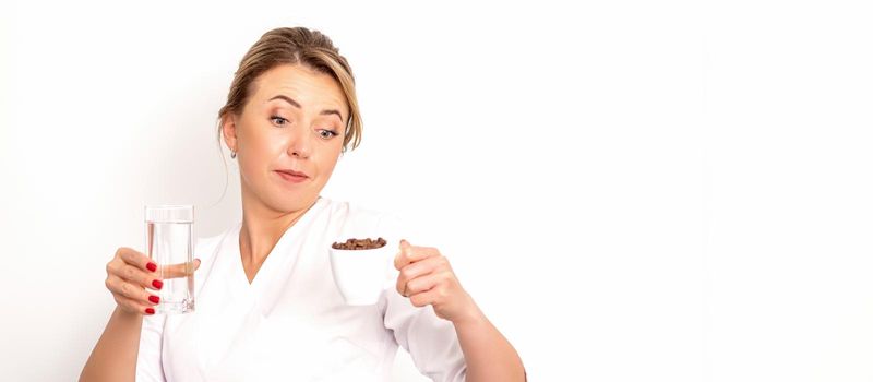 Coffee with water. The female nutritionist holds a cup of coffee beans and a glass of water in her hands on white background