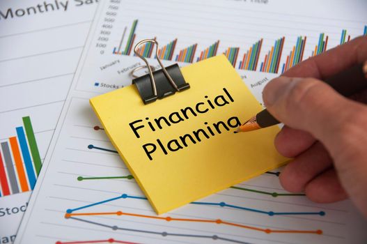 Financial planning text on yellow notepad with financial data analysis background. Financial planning concept