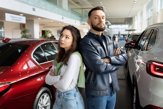 a young married couple cannot agree on the choice of a new car at a car dealership.
