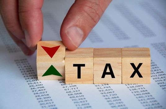 Tax word on wooden blocks with hand turn wooden block with up and down symbol. Taxation concept.