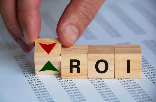 Return on investment text on wooden blocks with hand turn wooden block with up and down symbol. Investment concept.