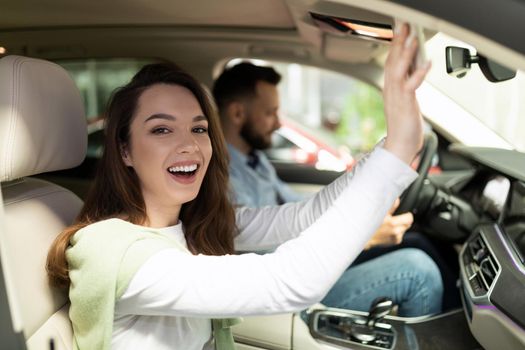 happy married couple just bought new cars in car dealership.