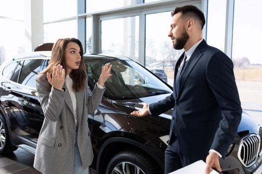 a woman defends her rights in a dealership arguing with a representative of a car dealership.