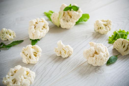 inflorescences of small raw cauliflower on a light wooden table
