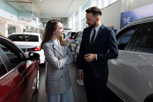 car dealership employees communicate among new cars.