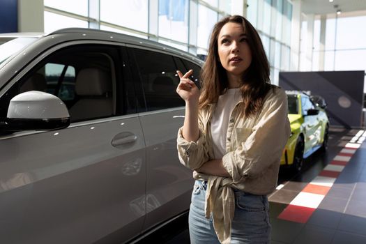 a young woman in a car dealership chooses an off-road family car for herself.