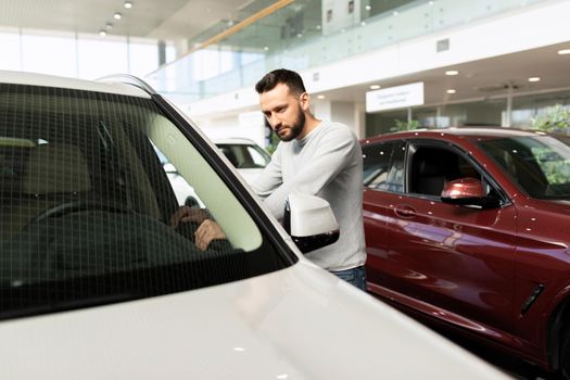 a man examines a car in a car dealership.