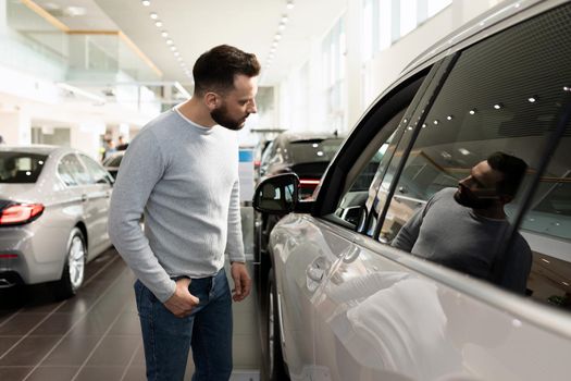 a man examines the range of cars in the showroom for a car dealership.