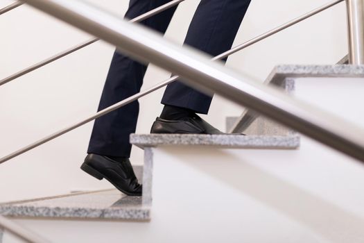 a businessman moves up the steps to the top, close-up of the steps and male legs.