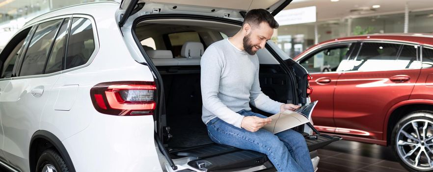 a man buys a new car and draws up an insurance policy for it at a car dealership.