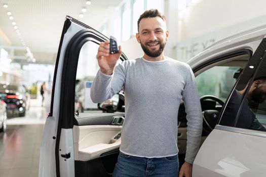 a middle-aged man next to the car he bought and insured demonstrates the ignition keys.