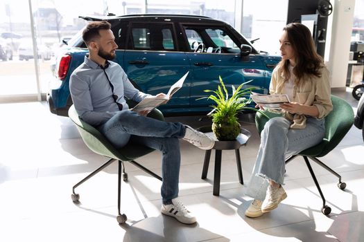 a young married couple picks up insurance for a car in a car dealership.