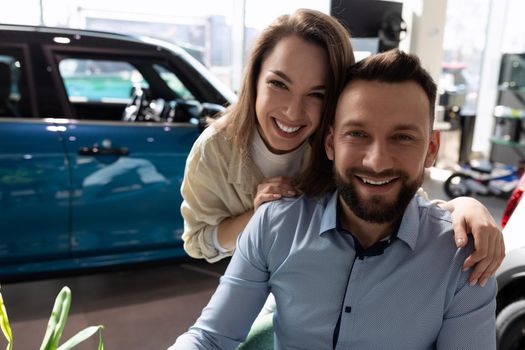 a happy married couple insured their car at a car dealership with an insurance company.