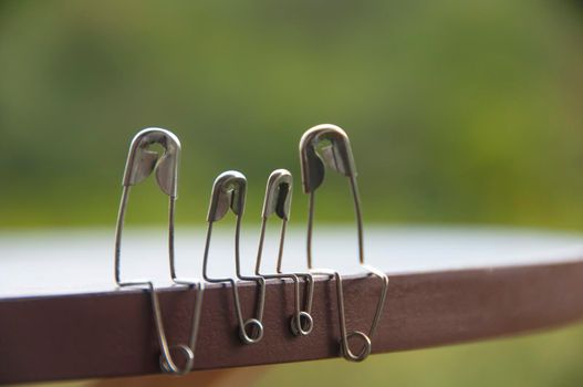 Model safety pin of family sitting on wooden table with blurred nature background. Copy space and family concept.