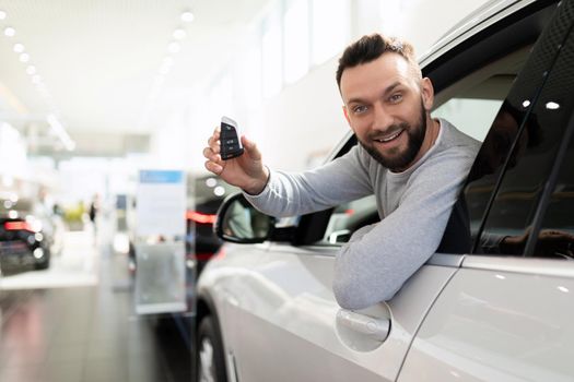 happy man bought a car in a car dealership and insurance for it.