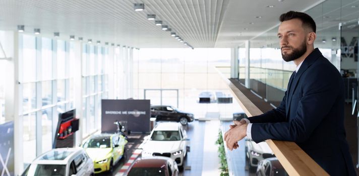portrait of a car business owner against the backdrop of a car dealership.
