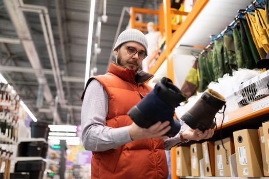 buyers a man in a hardware store chooses shoes for work at a construction site.