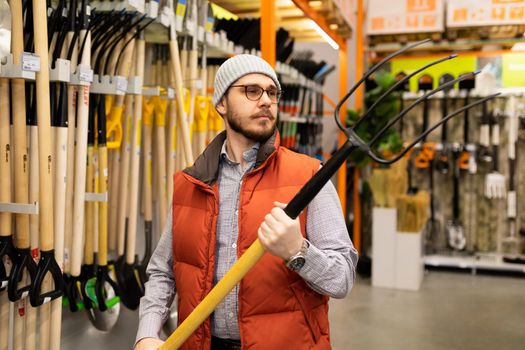 the buyer in the store chooses a new garden pitchfork.