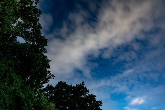 Dark blue sky on long exposure with moving clouds at night 