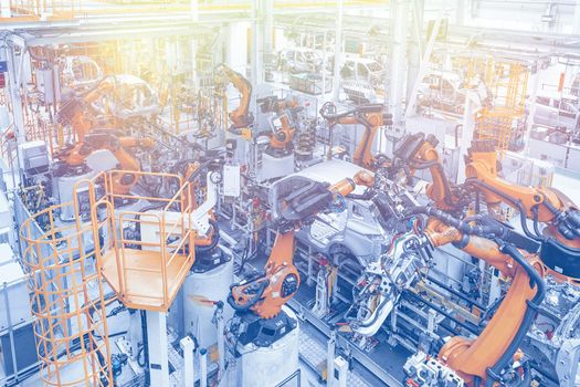 Photo of automobile production line. Welding car body. Modern car assembly plant. Top view in blue and yellow tone.