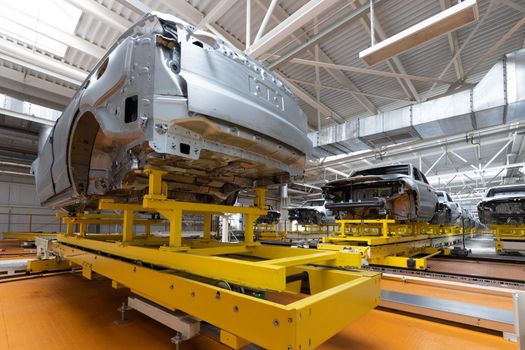 Car bodies are on assembly line. Factory for production of cars. Modern automotive industry. A car being checked before being painted in a high-tech enterprise.