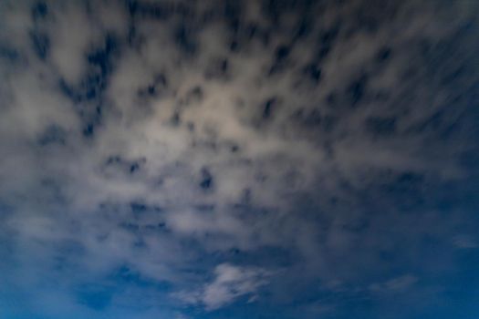 Dark blue sky on long exposure with moving clouds at night 