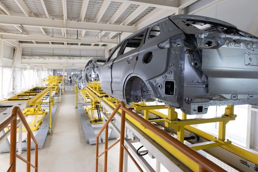 Car bodies are on assembly line. Factory for production of cars. Modern automotive industry. A car being checked before being painted in a high-tech enterprise.