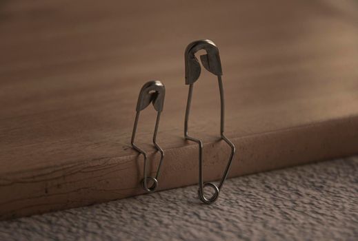 Model safety pin of parent and child sitting on wooden cover with customizable space for text or ideas. Family concept.