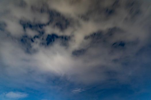 Dark blue sky on long exposure with moving clouds at night 