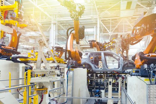 Photo of automobile production line. Welding car body. Modern car assembly plant. Auto industry. Yellow tone.