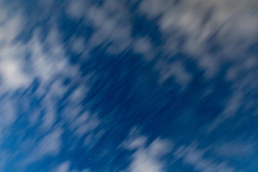 Dark blue sky on long exposure with moving clouds at night 