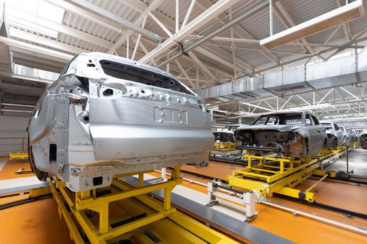 Car bodies are on assembly line. Factory for production of cars. Modern automotive industry. A car being checked before being painted in a high-tech enterprise.