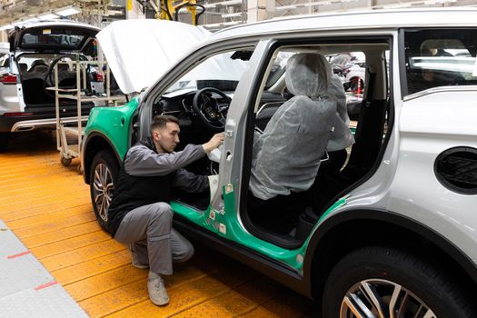 Minsk, Belarus - Dec 15, 2021: Car bodies are on assembly line. Factory for production of cars. Modern automotive industry. Electric car factory, conveyor, workers.