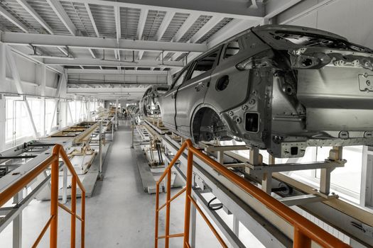 Car bodies are on assembly line. Factory for production of cars. Modern automotive industry. A car being checked before being painted in a high-tech enterprise.