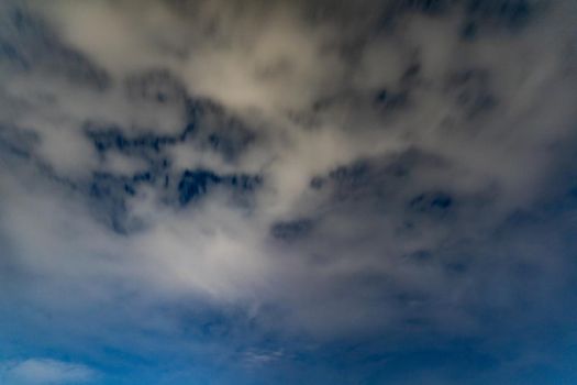 Dark blue sky on long exposure with moving clouds at night 