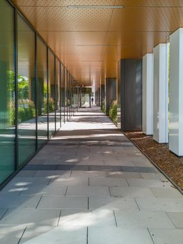 Long tunnel with pillars next to new modern corporate building