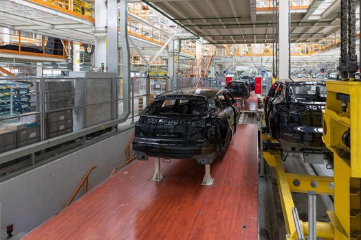 Car bodies are on assembly line. Factory for production of cars. Modern automotive industry. A car being checked before being painted in a high-tech enterprise.