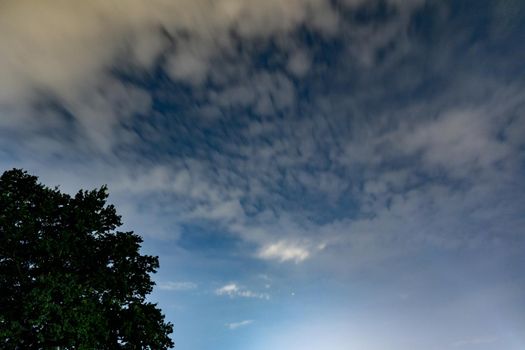 Dark blue sky on long exposure with moving clouds at night 