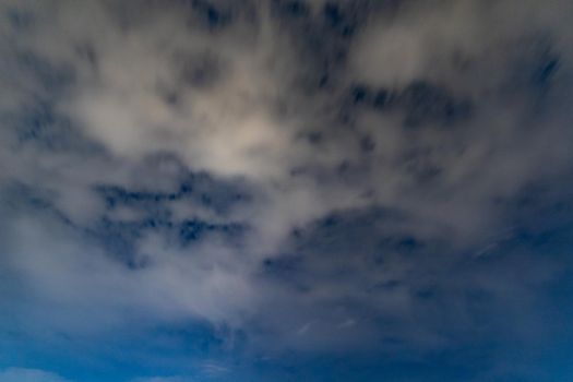 Dark blue sky on long exposure with moving clouds at night 